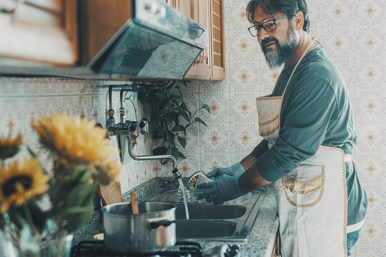 Un uomo lava i piatti foto iStock. - RIPRODUZIONE RISERVATA